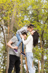 Happy family: mother, father and little daughter outdoor. Parents giving child