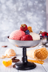 Set of ice cream scoops of different colors and flavours with berries, chocolate on wooden background