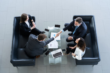 Business people shaking hands, finishing up a meeting, top view.
