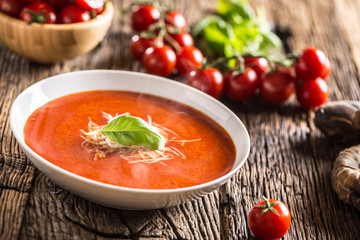 Hot tomato soup parmesan cheese and basil leave on old oal table