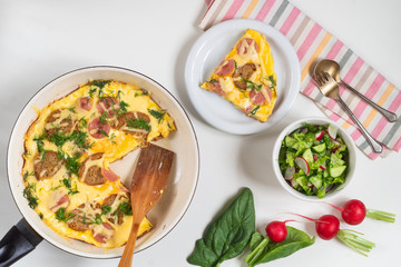 Omelet with croutons, sausages, cheese and dill in a pan