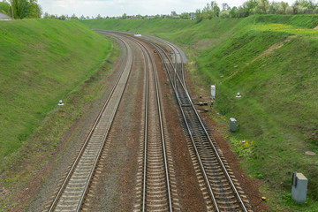 Fototapeta na wymiar The railway turns vertically through a spring green field. Railways