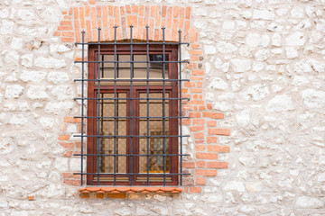 Fototapeta na wymiar Close up Window with iron bar grill in stone wall, stained glass window