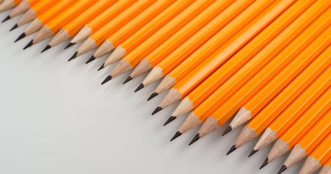 Yellow coated pencils apear sliding on white background. Close up view, shot on RED 6K camera