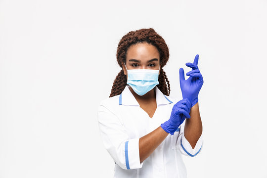 Image of african american nurse or doctor woman wearing medical face mask wearing disposable gloves
