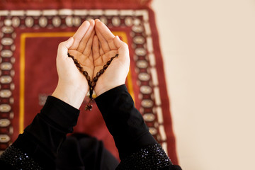 Prayer hands of a woman holding a rosary, with space for text