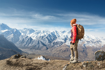 Fototapeta premium Portrait of photographer hipster tourist girl in sunglasses and a hat against the background of snow-covered Caucasus mountains. Photo travel concept