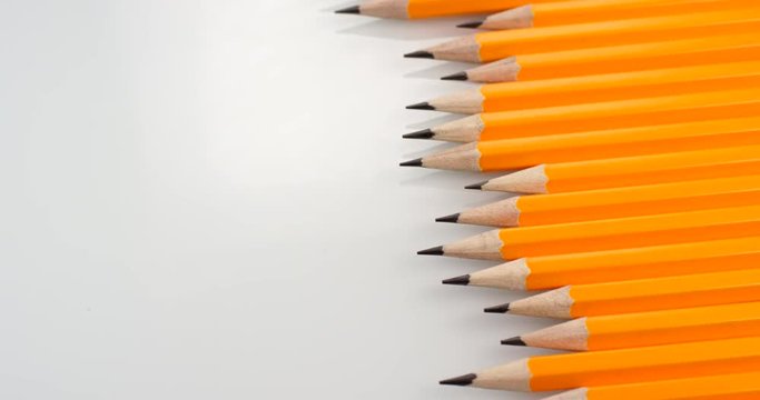 Yellow coated pencils apear sliding on white background. Close up view, shot on RED 6K camera