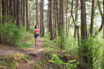 Obraz premium Athletic young woman in pink sneakers run in spring forest