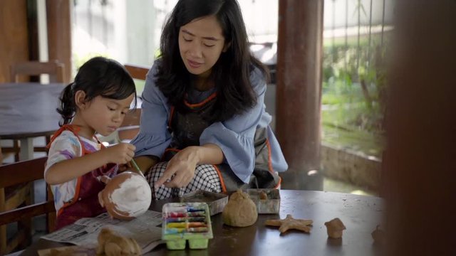 mother and daughter making ceramic pot in pottery workshop