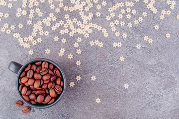 Obraz na płótnie Canvas Fragrant grains of black coffee in a black glass on a gray concrete background