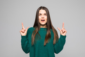 Young pretty woman pointed up wearing in green sweater isolated on gray background