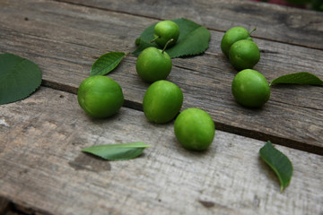 Green fresh plums on the wooden background
