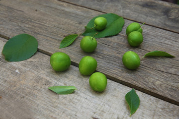 Green fresh plums on the wooden background