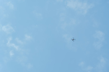 Obraz na płótnie Canvas Professional filming drone flies in the air at a low altitude against a blue sky. Drone makes photos. Modern new technology