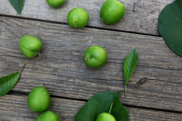 Green fresh plums on the wooden background