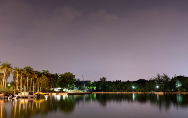 Fototapeta na wymiar Horizontal view of lake and nature during dusk with night stars and smooth reflection on waters