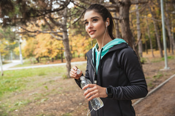 Smiling fitness woman listening to music with earphones