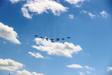 A group of ten aircraft in a blue sky with white clouds, selective focus