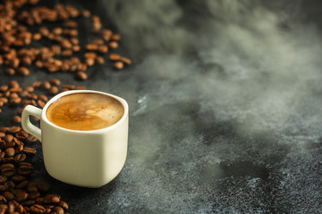 coffee in a white cup and coffee grain scattered on the table (freshly brewed hot drink with foam). food background. top