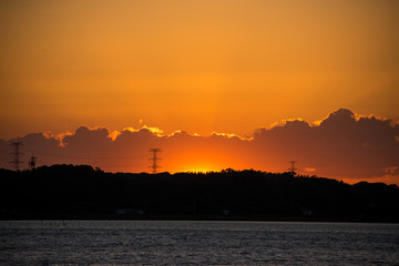 地平線の雲のかなたに沈む夕日の残照