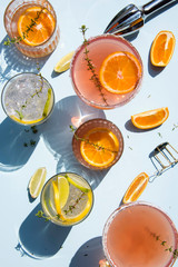 Trendy cocktails on light blue background with lemon and orange slices. Abstract conception.