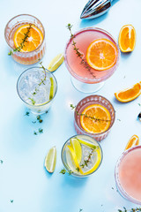 Trendy cocktails on light blue background with lemon and orange slices. Abstract conception.