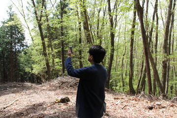 自然の中でスマホの電波を探している若い男性