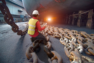 Stevedore, port controller, Port Master, surveyor inspect under bottom hull chains bundle of ship in floating dry dock yard, recondition of overhaul repairing and repainting, working in dry dock 