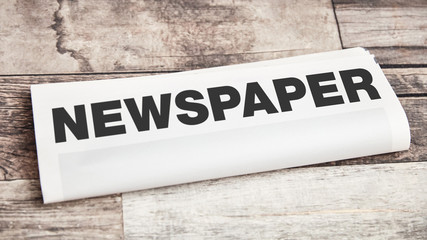 Gefaltete Zeitung mit Newspaper Text auf Holz