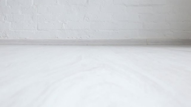 A child in jeans walks on the white floor. Feet close up.