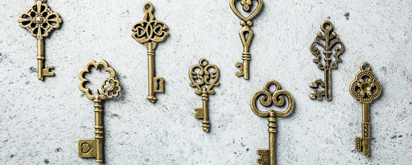 Top view of many different old keys on old gray concrete background. Concept with copy space. Banner.