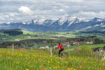 Fototapeta na wymiar senior woman mountainbiking on a e-mountainbike in early spring, in the Allgaeu Area, a part of the bavarian alps,Germany
