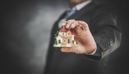 businessman holding house in hand, insurance and mortgage concept