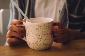 woman hands holding mug of hot drink that standing on wooden table