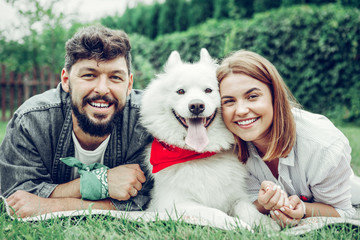 Portrait of couple laying on the grass with a samoyed.
