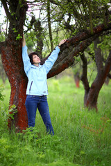 Beautiful mature woman posing for the camera in the spring garden. The girl enjoys the flowering of apple trees.