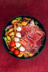 Salad made with cooked pasta, mixed green salads, cherry tomatoes, Mozzarella cheese and smoked ham...
