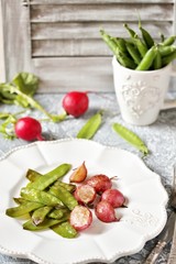 Fried young peas and radish pods. In the style of Provence. light background. Soft focus