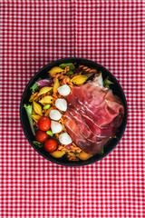 Salad made with cooked pasta, mixed green salads, cherry tomatoes, Mozzarella cheese and smoked ham...