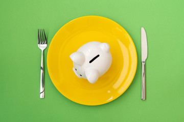 Plate with piggy bank on green background
