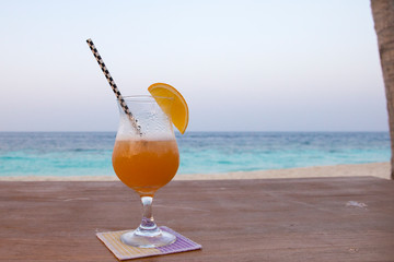 Tropical orange cocktail at sunset on a beautiful Maldives island 