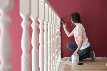 young beautiful woman painting a ledge ballustrade white with a brush