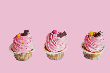 three cupcakes on a pink background isolated