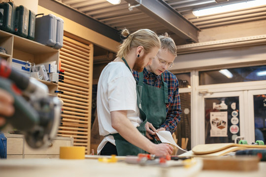 Teacher and student carpenters discuss the details of the new product taking into account all the wishes of the customer. Concept of continuity of experience