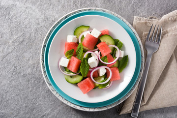 watermelon salad with feta cheese,mint,onion and cucumber on gray background. Top view