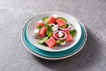 watermelon salad with feta cheese,mint,onion and cucumber on gray background. 