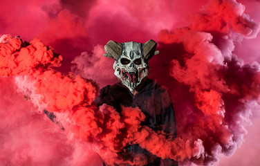 Devil with scary mask surrounded by red smoke