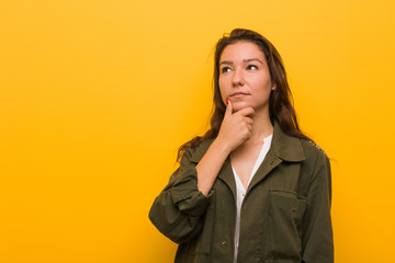 Young european woman isolated over yellow background looking sideways with doubtful and skeptical expression.