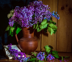 Lilac in a ceramic vase, a book and an hour on the table